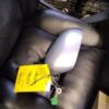 A car mirror is sitting on the arm of a chair.