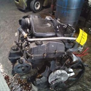 A car engine sitting on the floor of a garage.