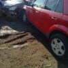 A red car is parked in the mud